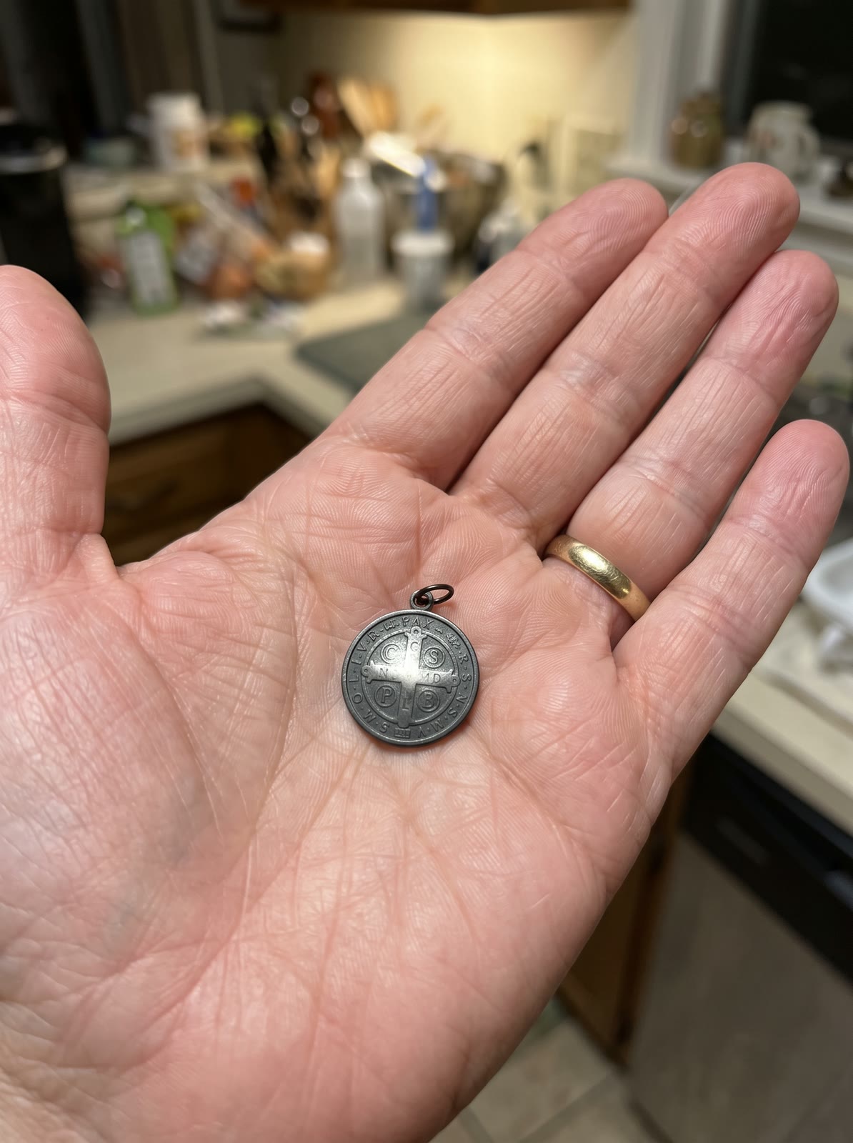 A small dark medal in a woman’s palm, its letters unreadable