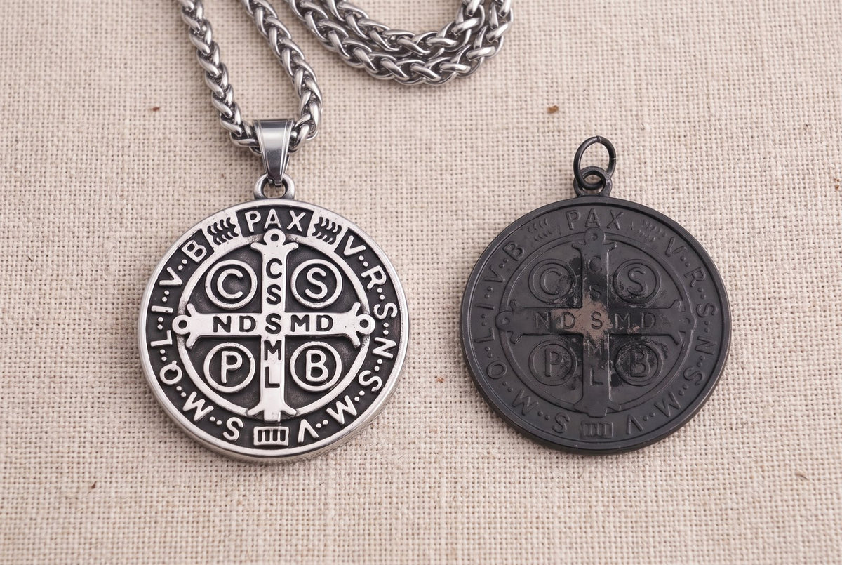 The St Benedict medal beside a flat black store medal on linen