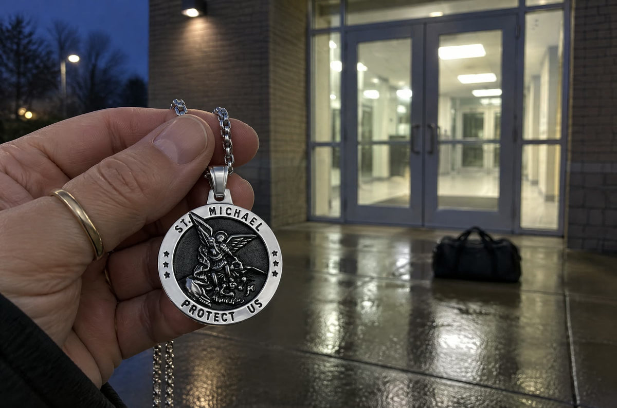 Before dawn at the glass doors of a government building, a mother’s hand holds up a silver St Michael medal, a duffel bag on the wet pavement