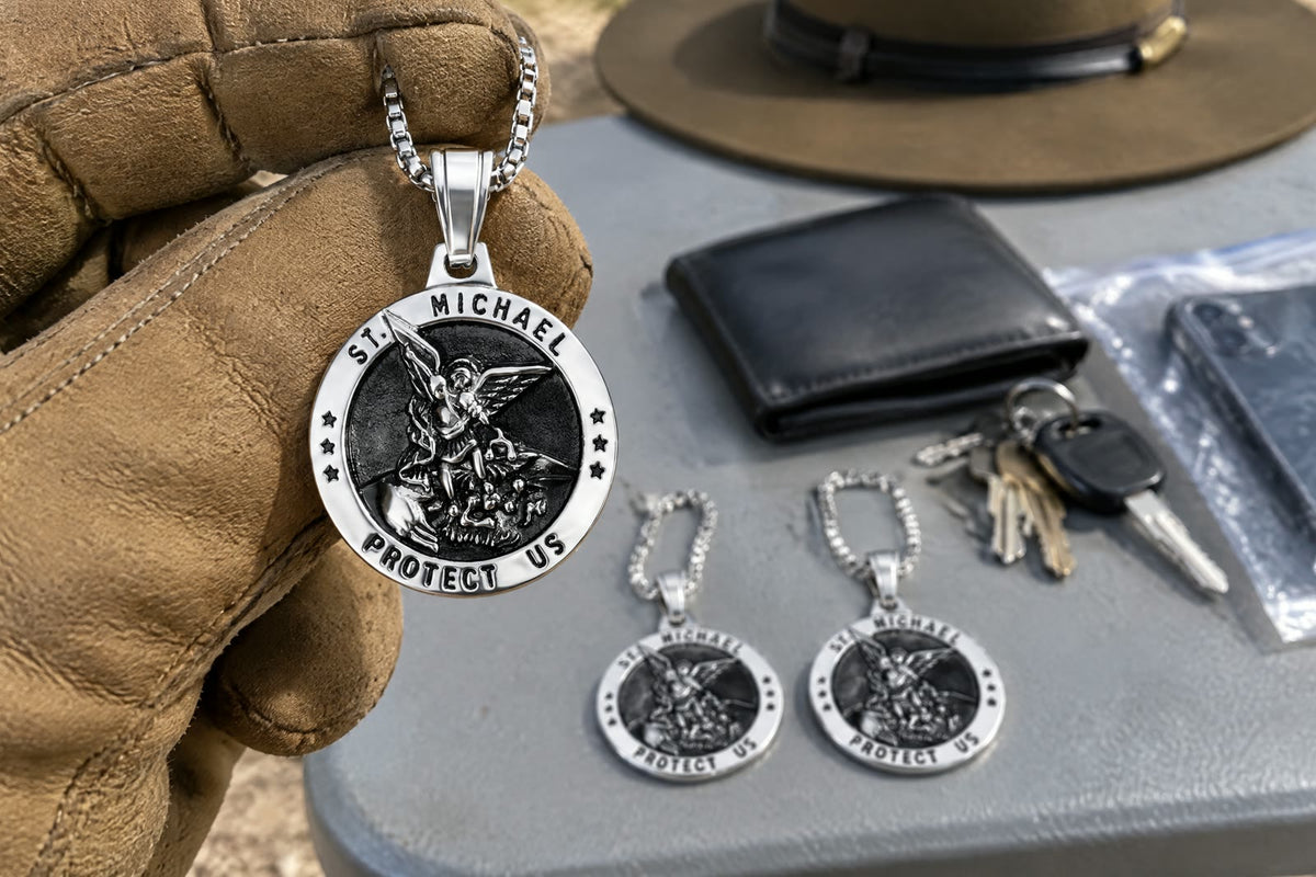A gloved hand raising a silver St Michael medal over a folding table with two more medals, a wallet, keys and a phone in a clear bag