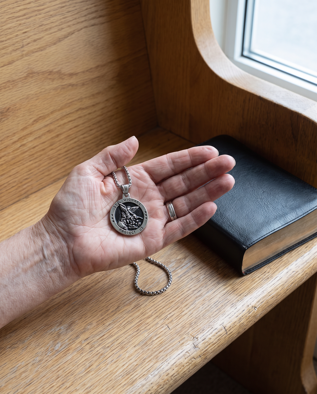The St Michael medal in a woman’s palm over a church pew