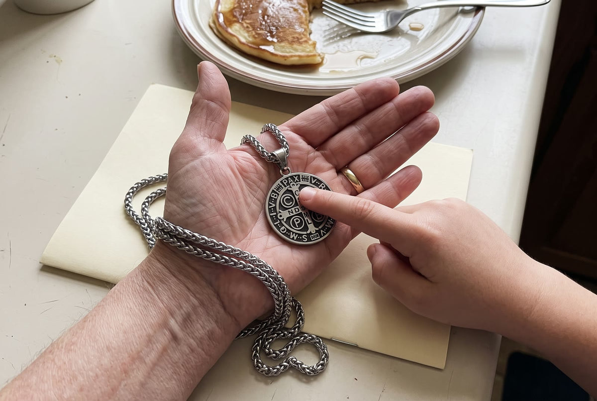 A boy’s finger on the letter C of the St Benedict medal in his grandmother’s palm