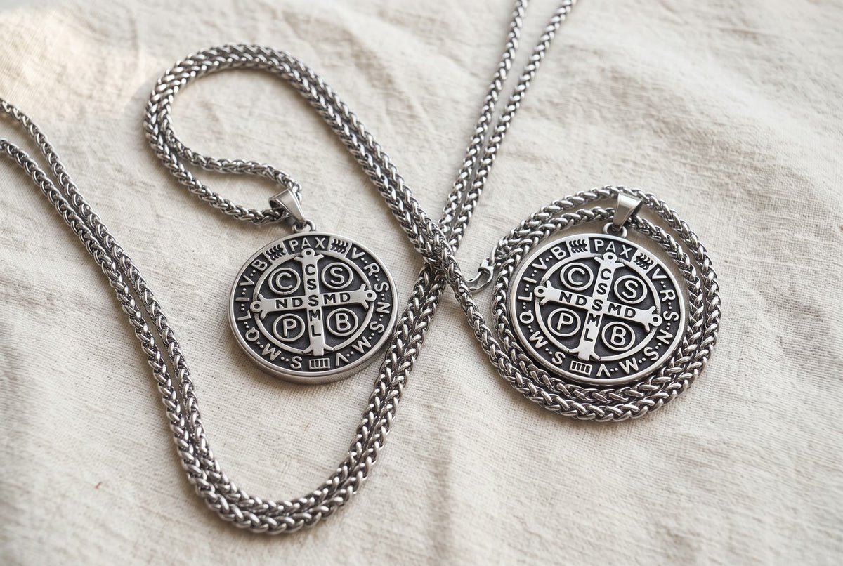 Two identical St Benedict medals on linen, their chains crossing