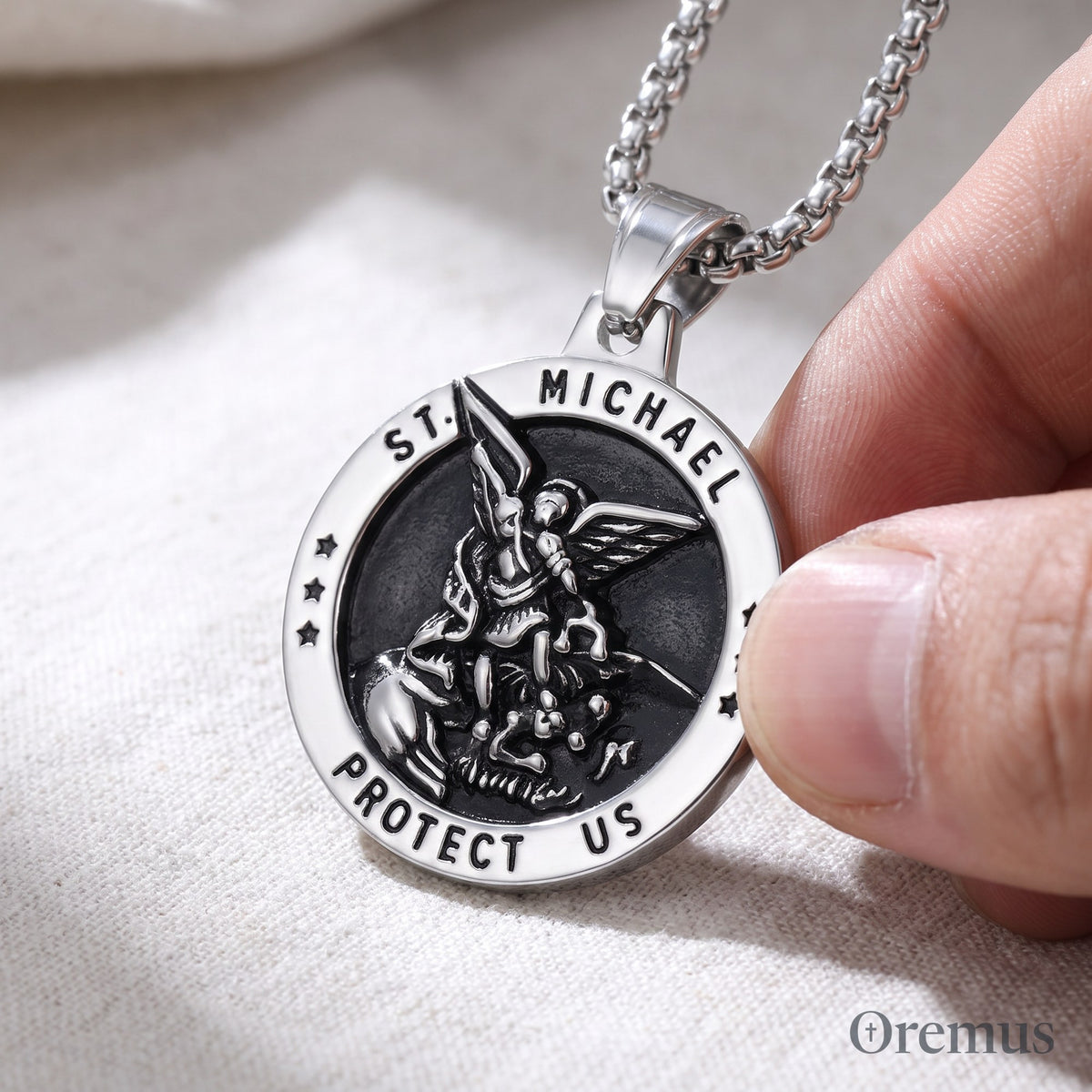 The St Michael medal in silver held between thumb and finger