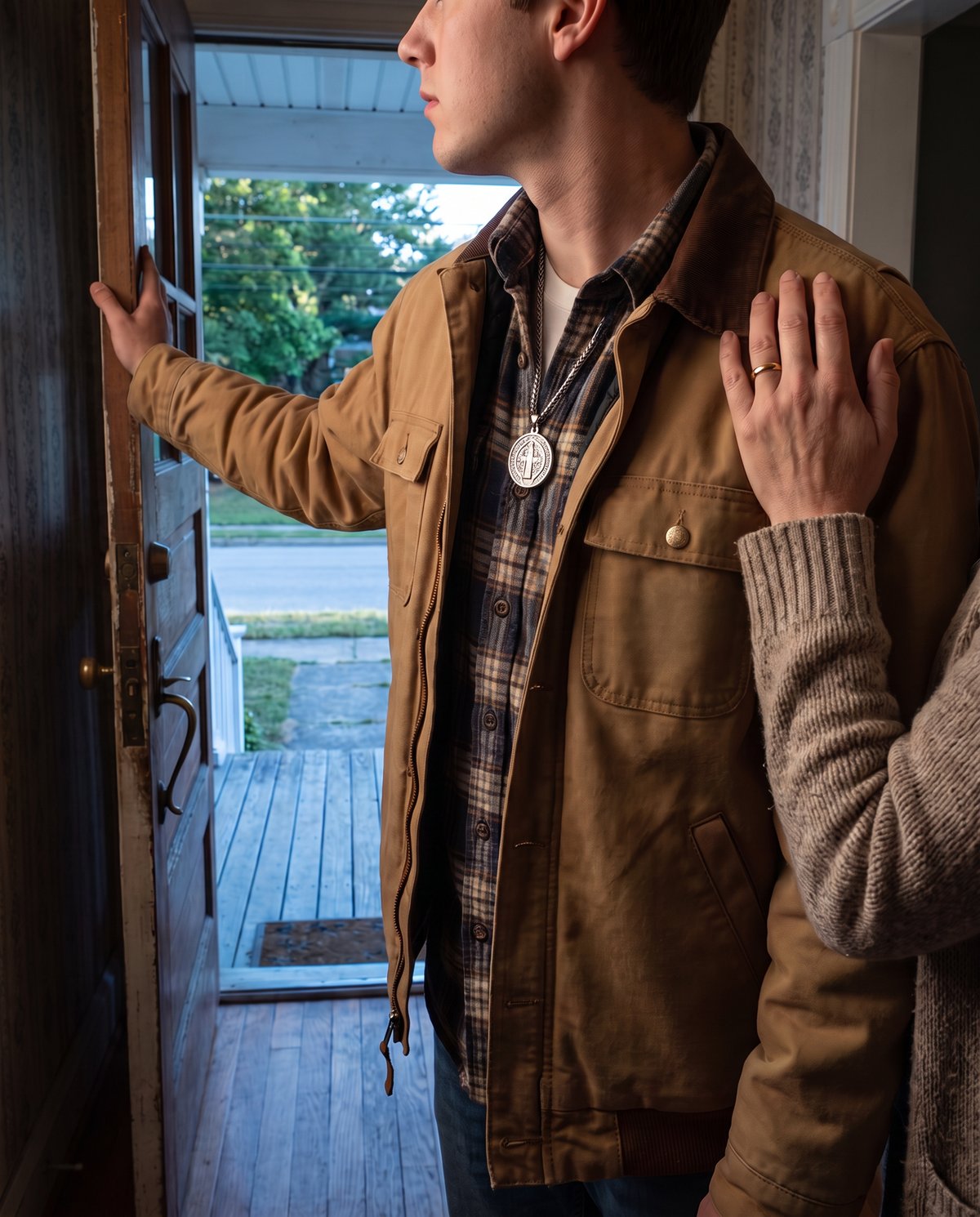 A young man leaving through the front door, the medal at his collar, his mother’s hand on his shoulder