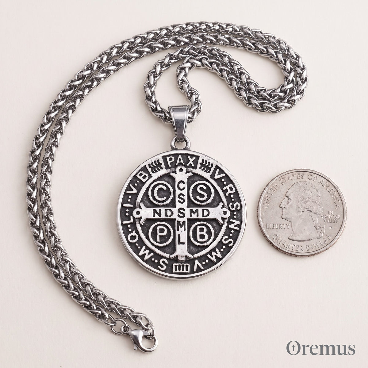 The St Benedict medal on its wheat chain beside a quarter